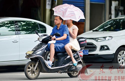 一人骑车一人打伞，险