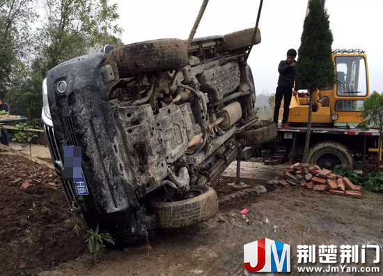 图为:吊车将翻入田埂内的越野车吊起