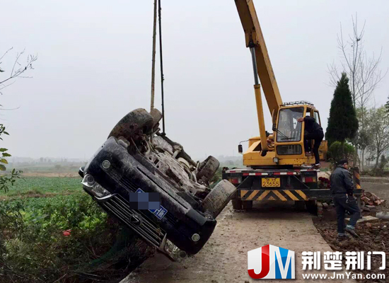 图为:吊车将翻入田埂内的越野车吊起