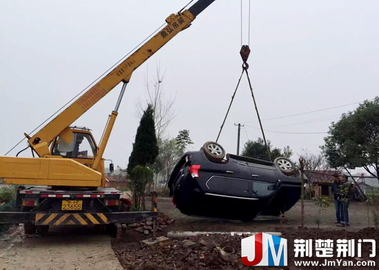 图为:吊车将翻入田埂内的越野车吊起