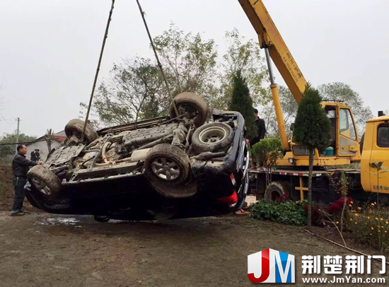 图为:吊车将翻入田埂内的越野车吊起
