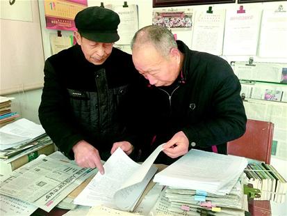 图为：年过花甲的杨书义、罗贤能翻看在外打工的会员作品，商量着推荐给出版社。