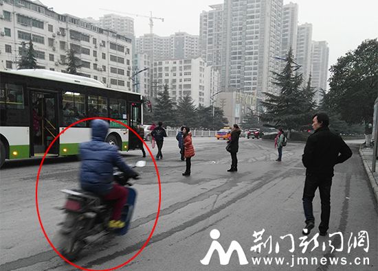摩托车从等公交的人群中间穿过