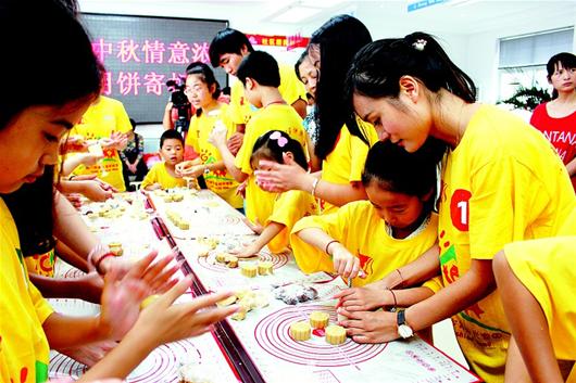 图为：社区义工教孩子们做月饼。（资料图片）