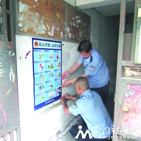 社区民警在居民楼张贴防诈骗宣传海报。荆门晚报通讯员 刘小娇 摄