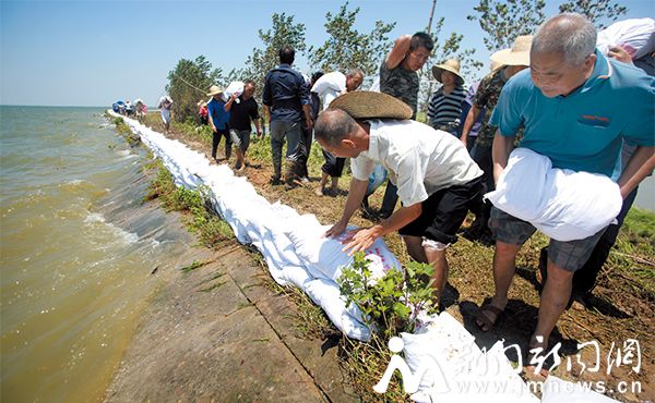 挥动铁锹，扛起沙包……7月22日，沙洋县毛李镇长湖幸福垸圩堤上，当地干部群众200多人冒着酷暑筑起一条长约1800米的“新防线”。--记者-朱舜-摄